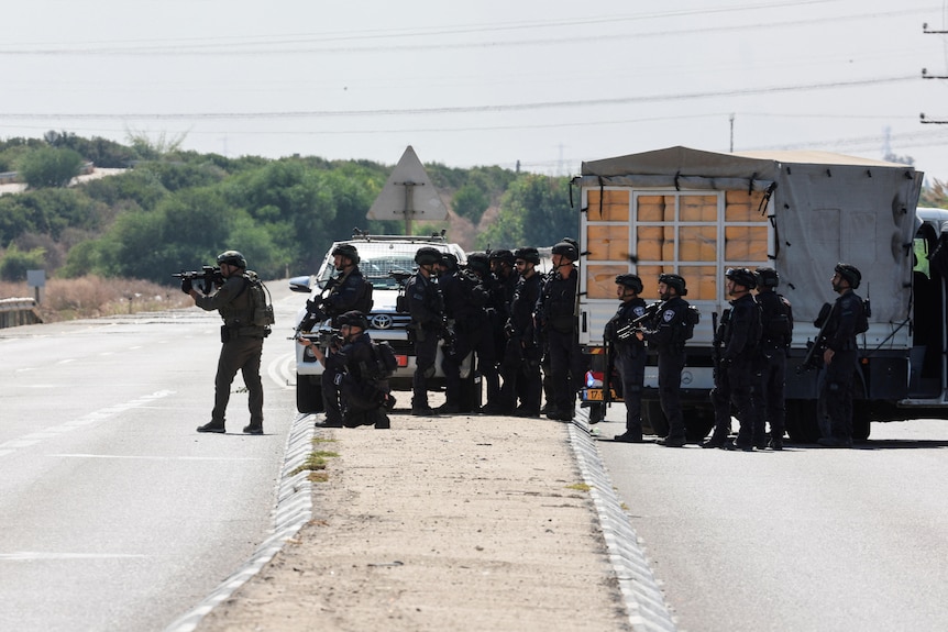 Securty forces gather in tactical gear on a road 