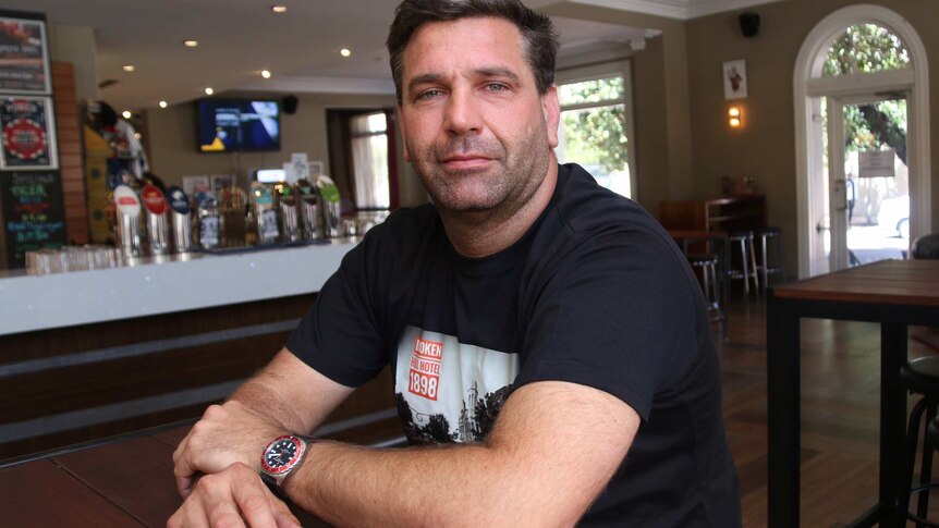 Broken Hill Hotel owner Nick Duncan poses for a photo sitting in the bar.