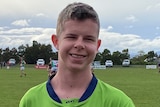 Mitchell Harwood holds a ball with his left hand at an Australian rules match in Tasmania.