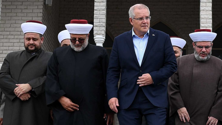 Scott Morrison, in a suit, walks out of a mosque with men in Islamic dress.