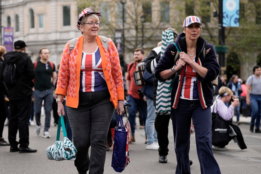 Women walk to find a spot to watch the coronation procession.