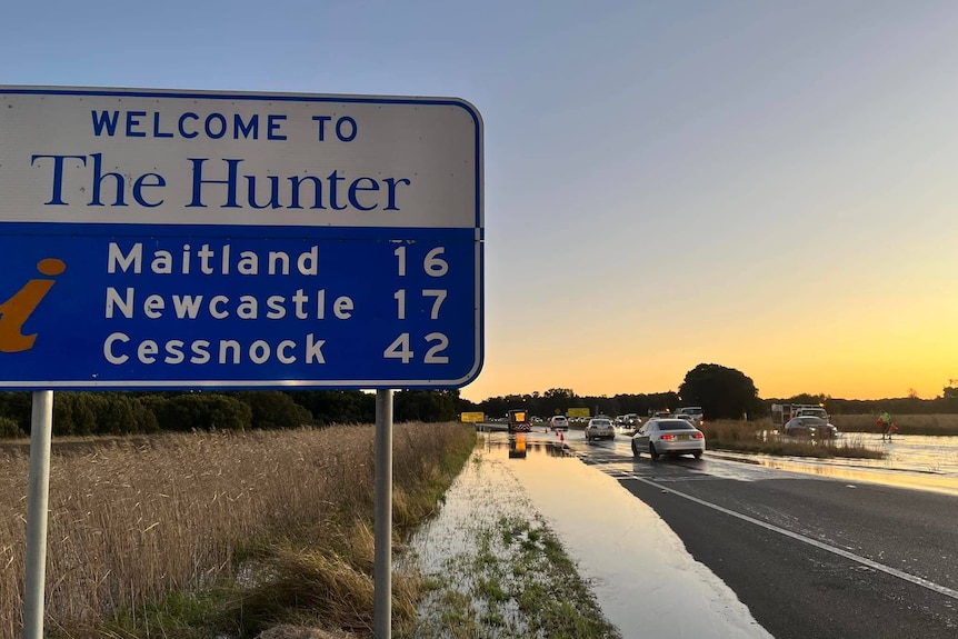 A sign saying welcome to the Hunter next to a flooded road