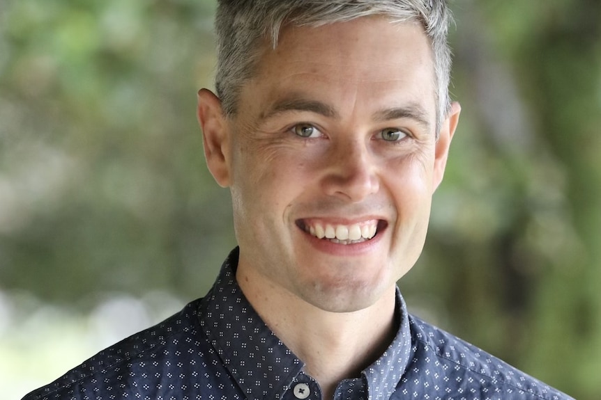 A smiling man with neat grey hair.