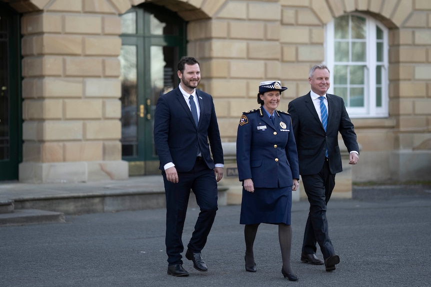 Police Minister Felix Ellis, new Police Commissioner Donna Adams and Premier Jeremy Rockliff walk away from a building.