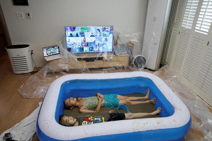 Children play in a mud pool during the Online Boryeong Mud Festival at their home during a live streaming event, in Gwangju.