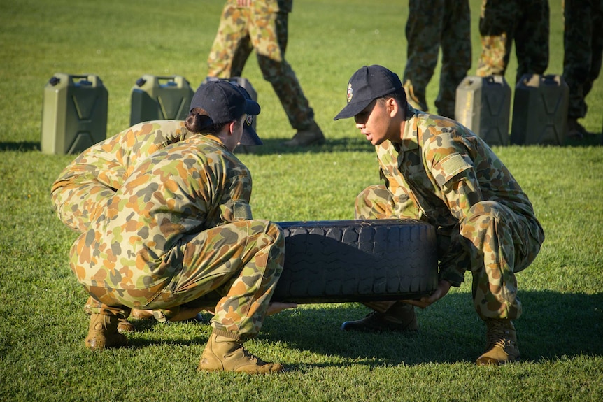 ADFA cadets, including one female, lift a tyre as part of their training.