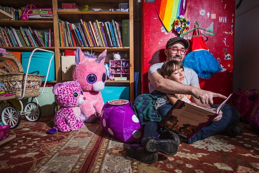 Father and daughter reading a book in a child's bedroom.