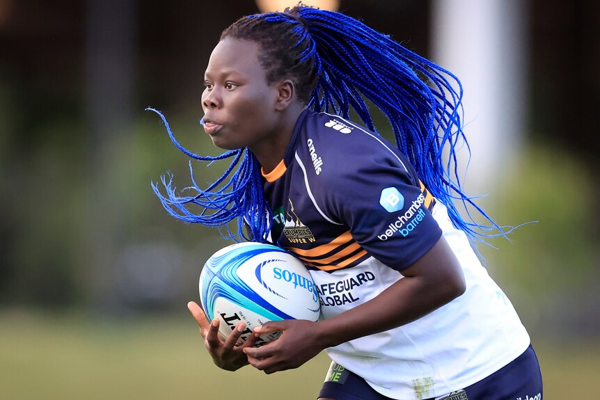 Biola Dawa holds the ball in both hands playing for the Brumbies.