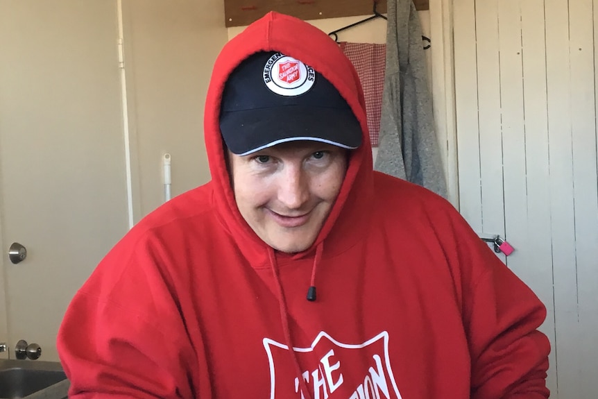 A man wearing a red hoodie looks at the camera.