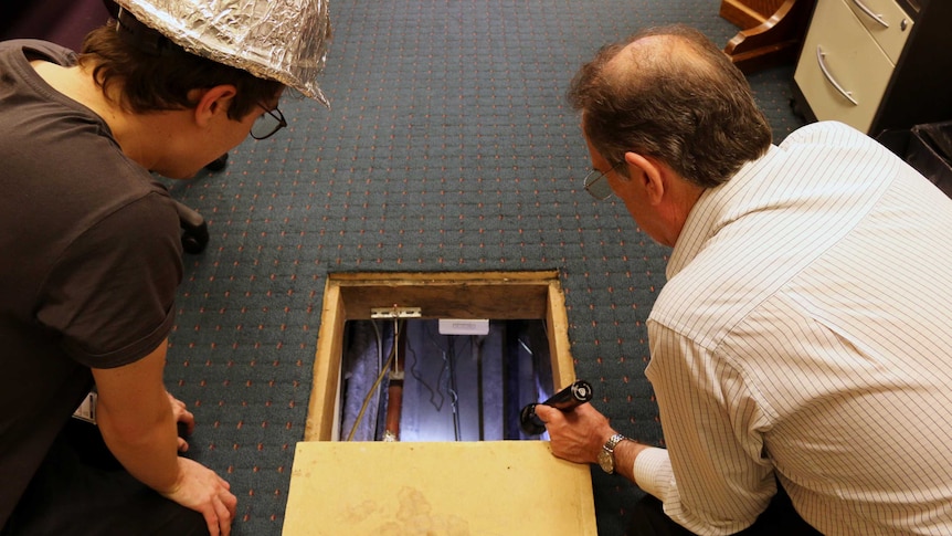 Historian Michael Evans shines a torch into the tunnel beneath Old Parliament House.