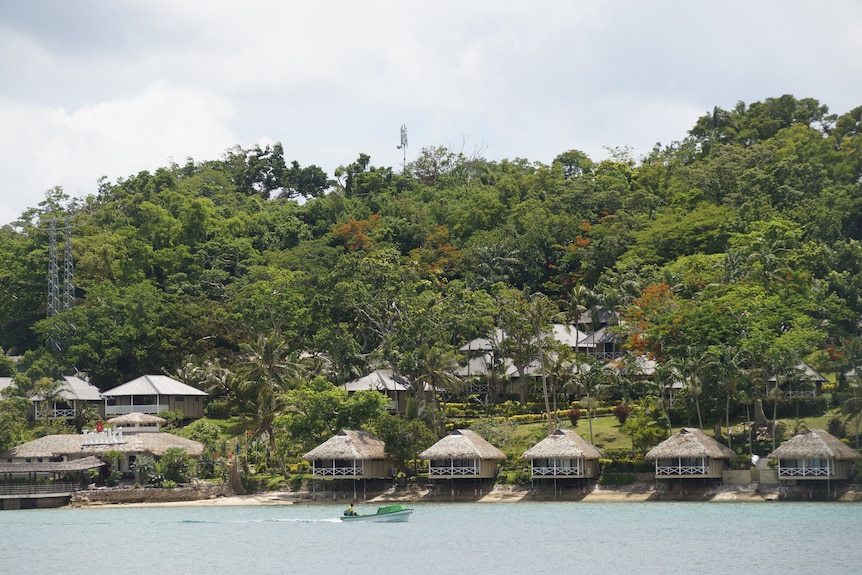 A view across Vila Bay of Iririki Resort, on Iririki Island, with a small boat moving in front of it.