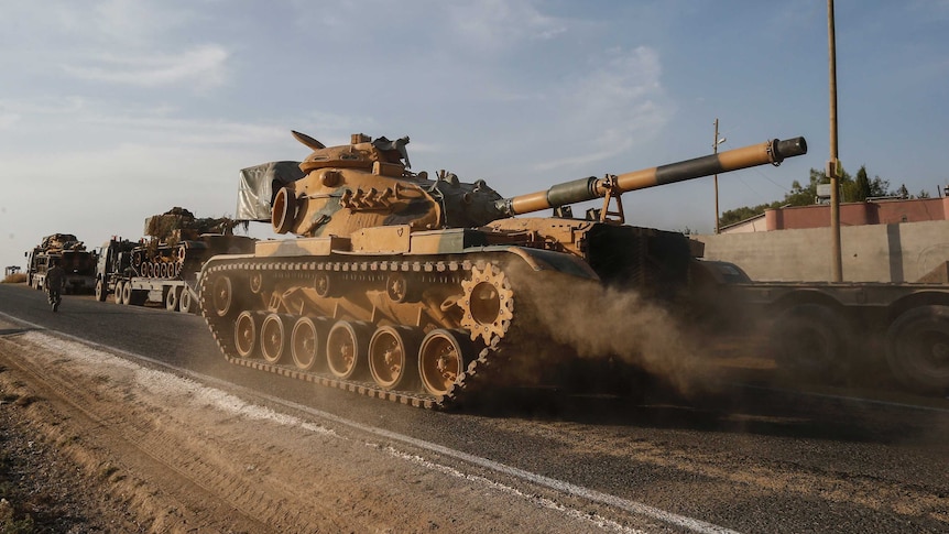 Turkish tanks drive down a dusty road in Syria.