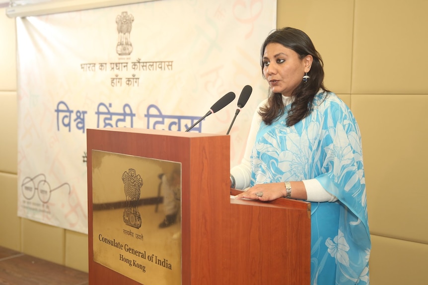 Priyanka Chauhan stands behind a lectern. 