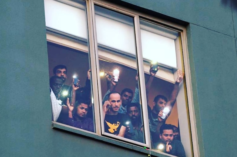 A group of men look through a sealed window.