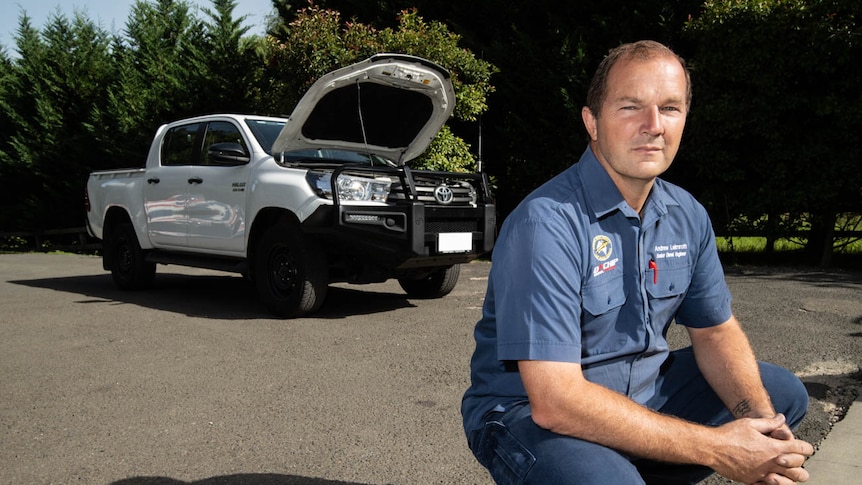 Berrima Diesel mechanic Andrew Leimroth crouches in front of a White Toyota Hi-Lux with the defective DPF.