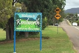 A welcome to Kenilworth signpost on the side of a road surrounded by green grass and trees