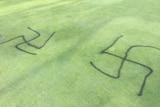 An aerial image of two swastikas pray painted onto a golf green.