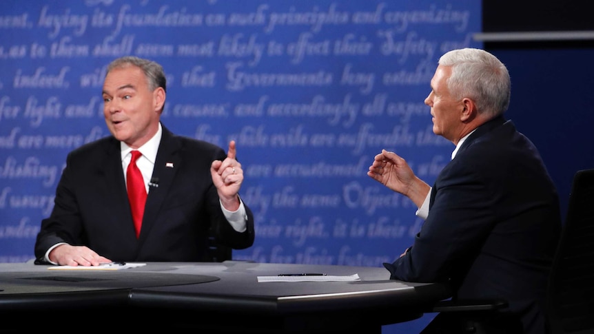Democrat Tim Kaine (left) and Republican Mike Pence discuss an issue with their hands raised during a VP debate.