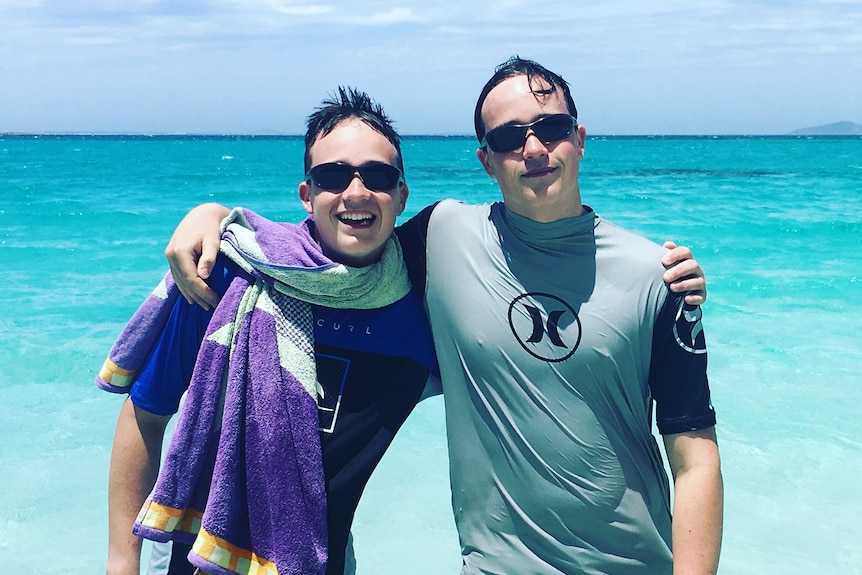 The pair have their arms around each other and stand knee-deep in turquoise water wearing goggles