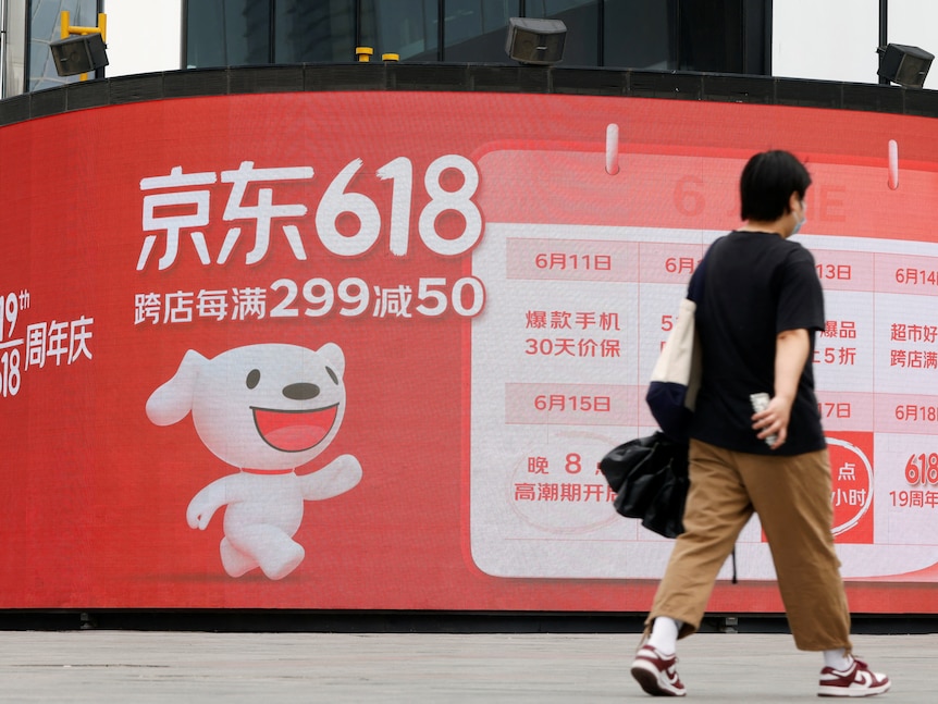 A Chinese pedestrian walks past advertisement about "618 sale". 