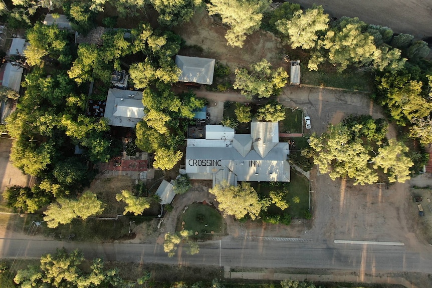 A drone view above a hotel sitting among a number of trees.