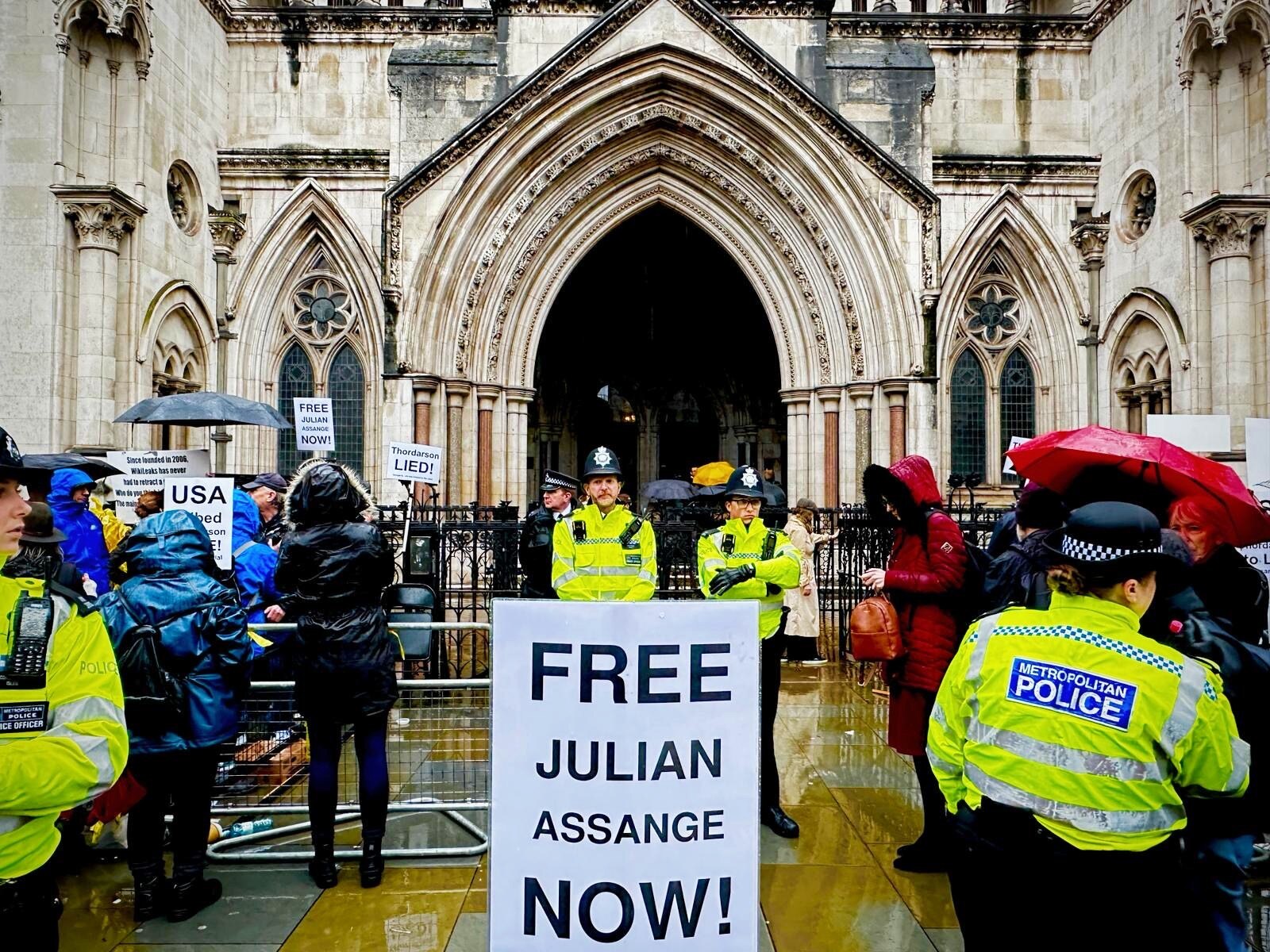 A large number of people, some police officers and some protesters, outside an old building