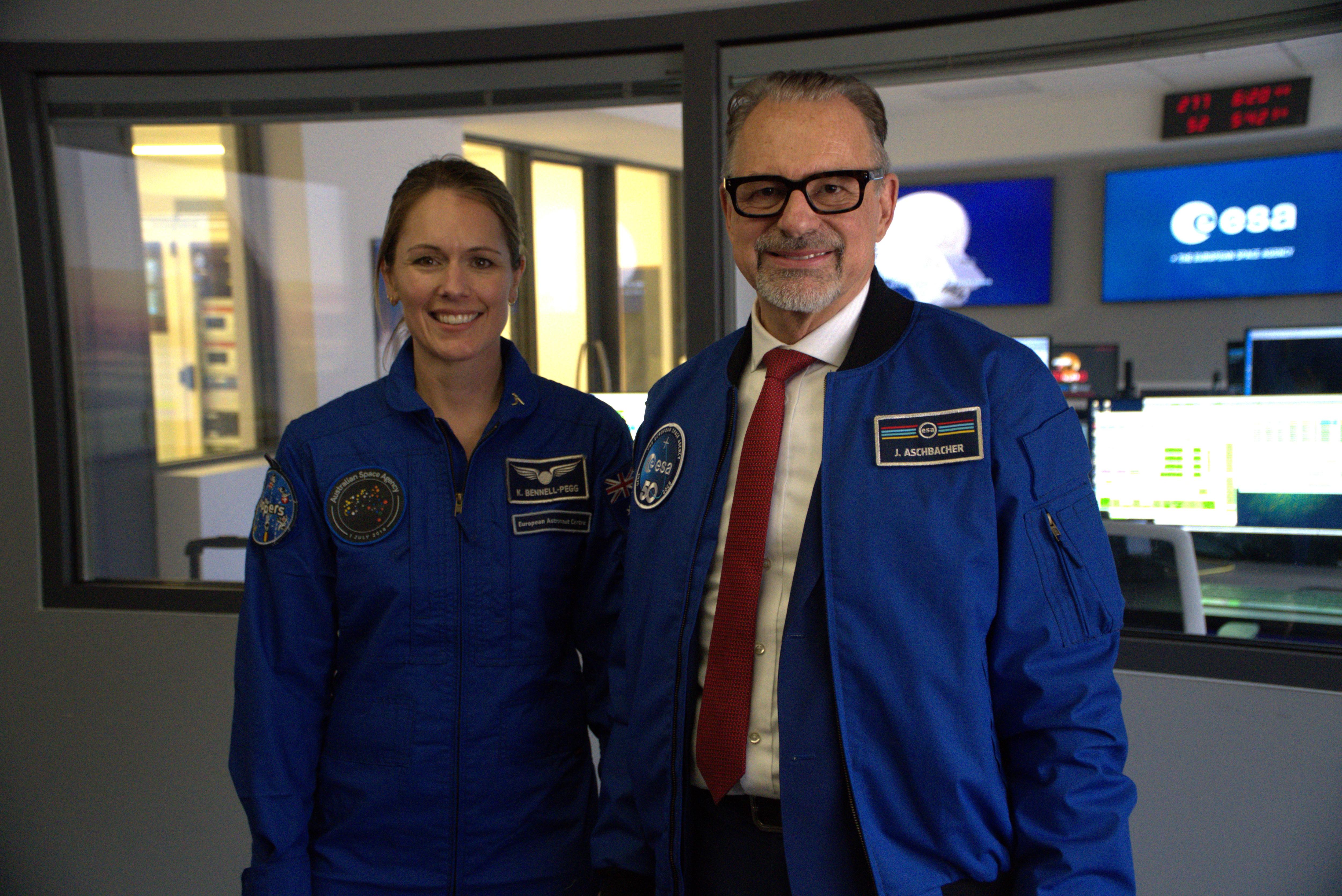 Katherine Bennell-Pegg  and Josef Aschbacher dressed in blue and smile next to each other inside an office.