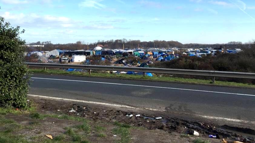 The highway where trucks pass next to the refugee camp, in the distance.