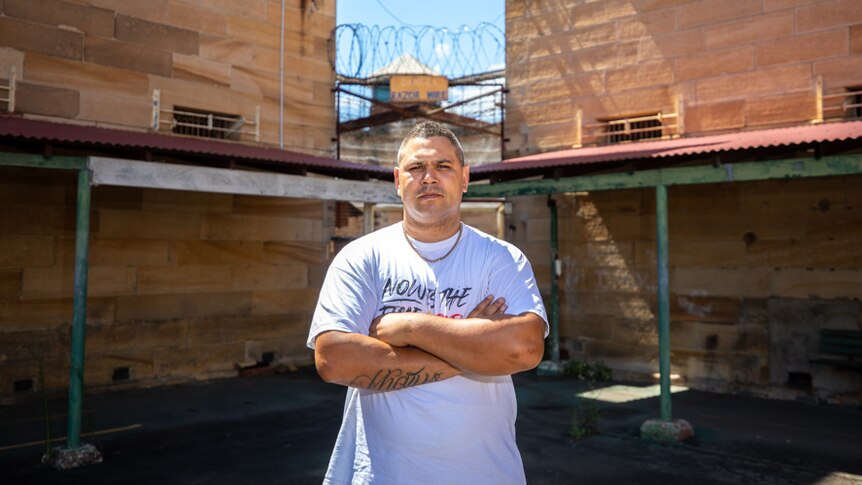 Keenan Mundine stands with arms crossed in front of prison gates