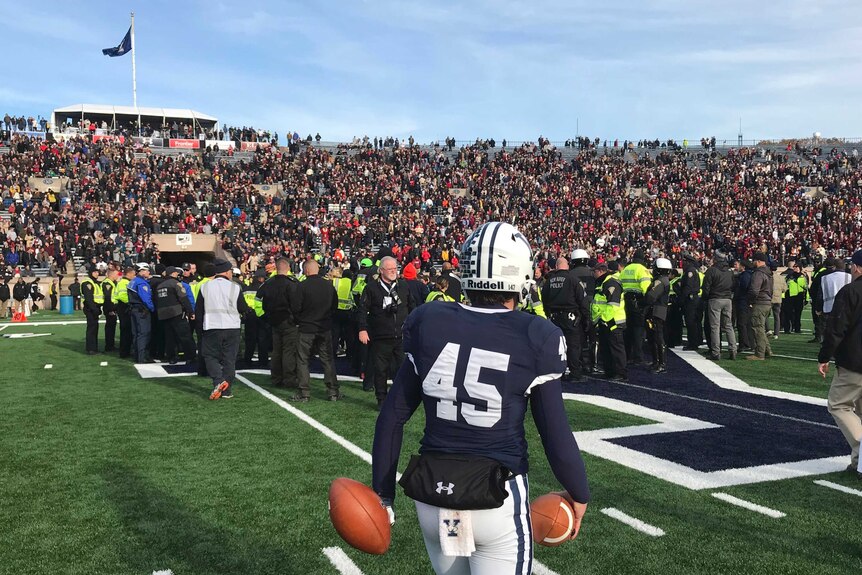 An American football player from Yale watches a protest take place on the field