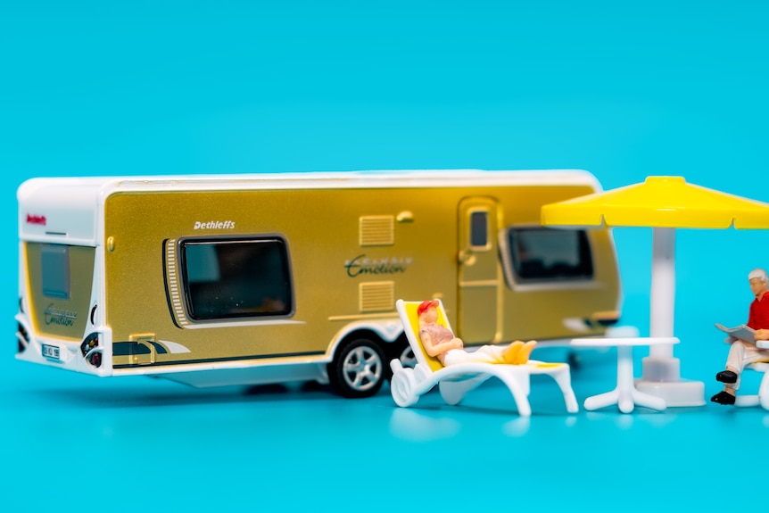 A photo of a miniature camper van and two miniature people.