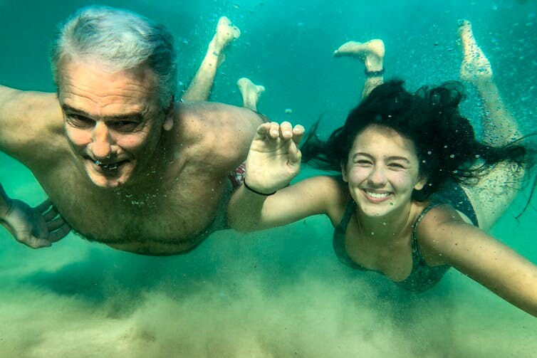 A father and daughter swim underwater
