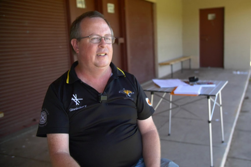 A man smiles in front of changing rooms.