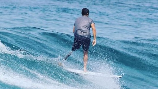 A man on his prosthetic leg surfs elegantly on a wave
