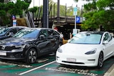 A white Tesla and black Volvo parked in 'electric vehicles only' bays, plugged into a charging station in Brisbane