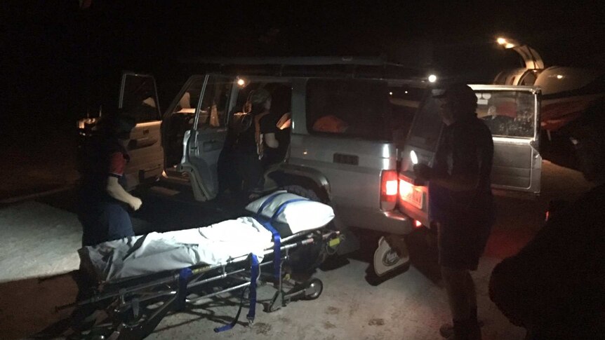 4WD with stretcher bed and people standing around it at night time