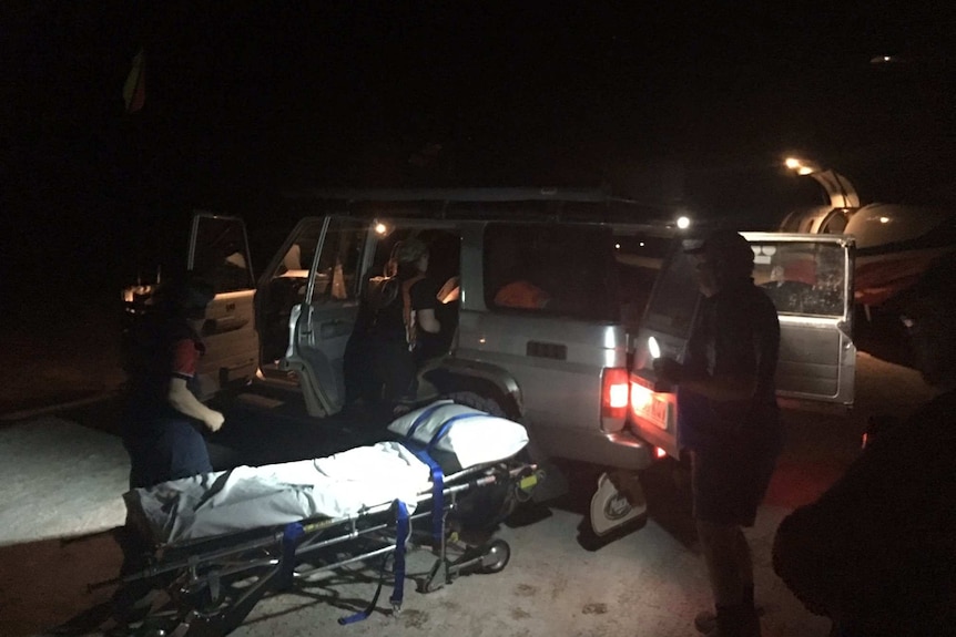 4WD with stretcher bed and people standing around it at night time