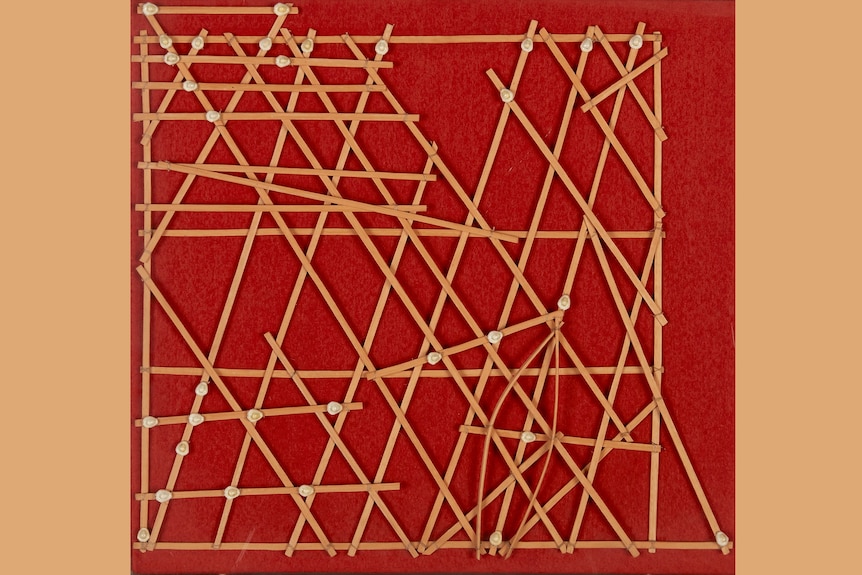 A stick chart made of thin strips of pandanus tied together in a rough grid, with some shells attached