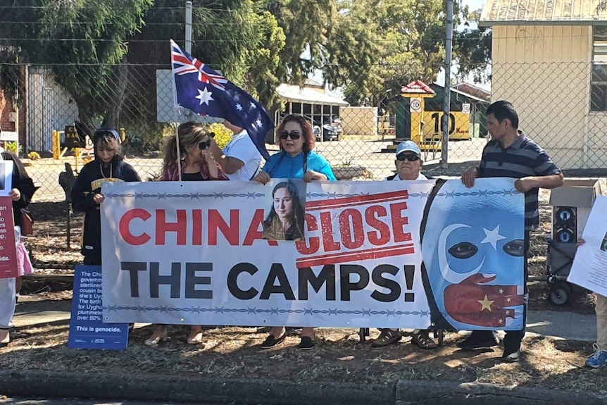 Members of Australia's Uyghur community holding banners in protest against China's communist party.
