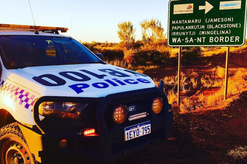 WA Police car next to a road sign on a remote patrol in the outback.  