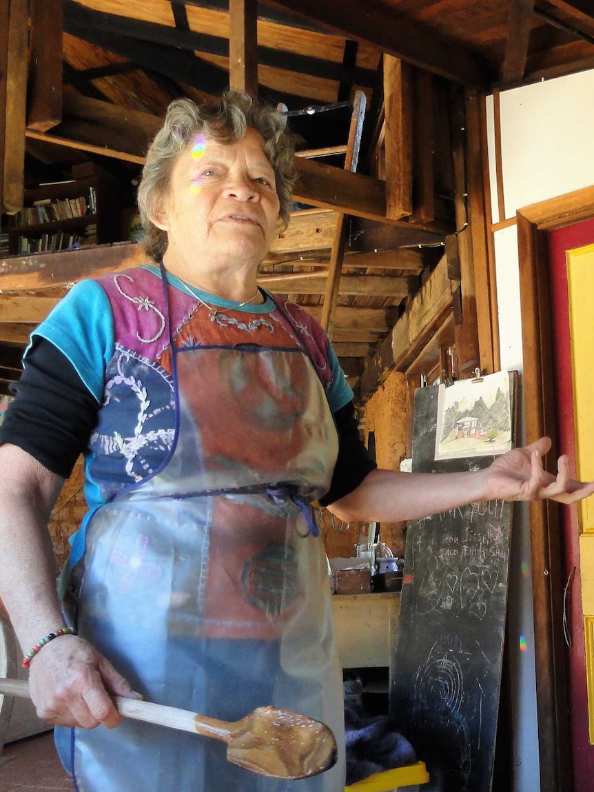 Medium shot of a woman standing in a kitchen holding a wooden spoon.