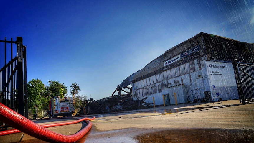 A firehose is pictured in the foreground with the warehouse behind