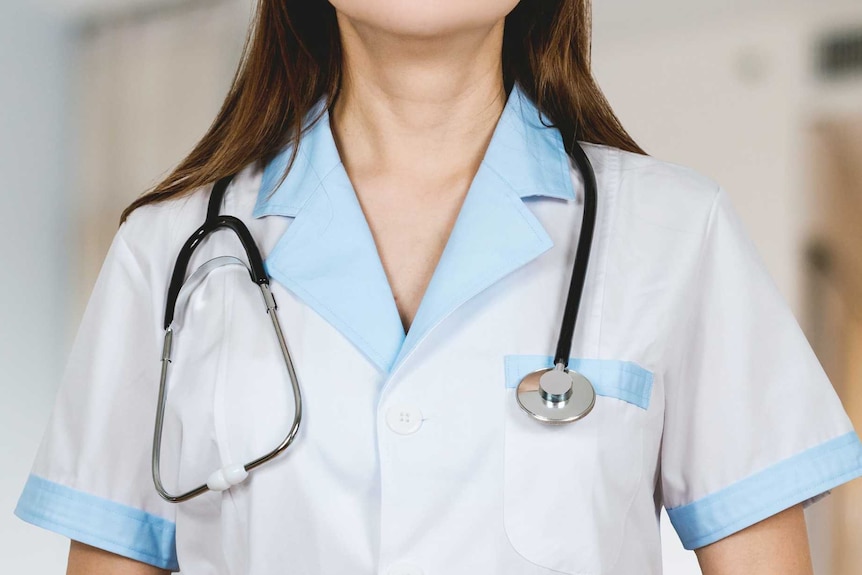 A female doctor wearing a white and blue coat with a stethoscope around her neck.