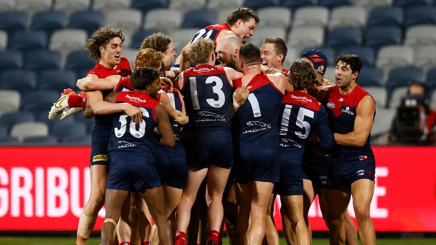 A group of Melbourne players pile on top of Max Gawn who has just kicked the winning goal after the siren.