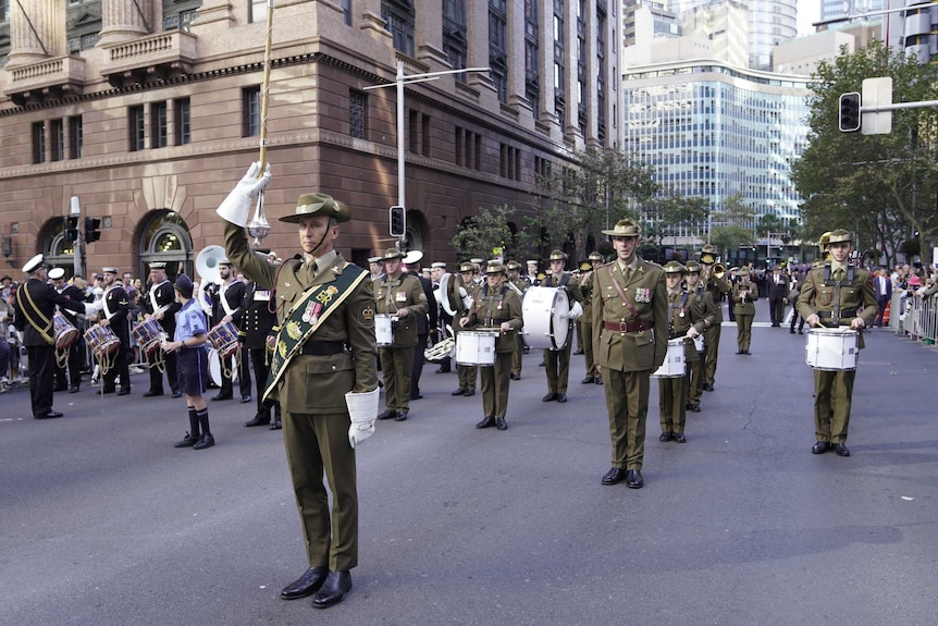 Soldiers dressed un uniform, holding instruments, ready to start the Anzac Day march in Sydney.