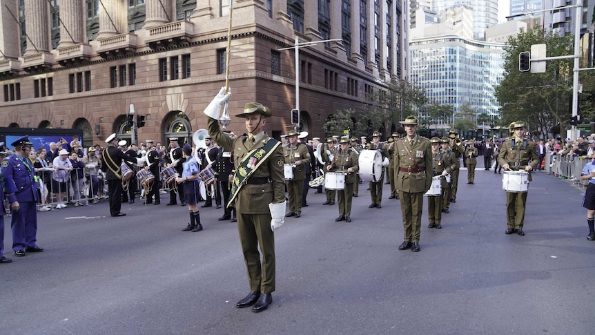 Soldiers dressed un uniform, holding instruments, ready to start the Anzac Day march in Sydney.