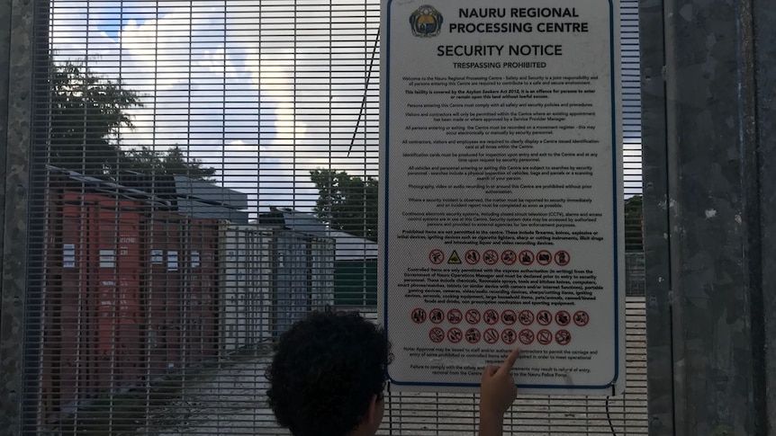 A child points to a security notice sign for the Nauru Regional Processing Centre