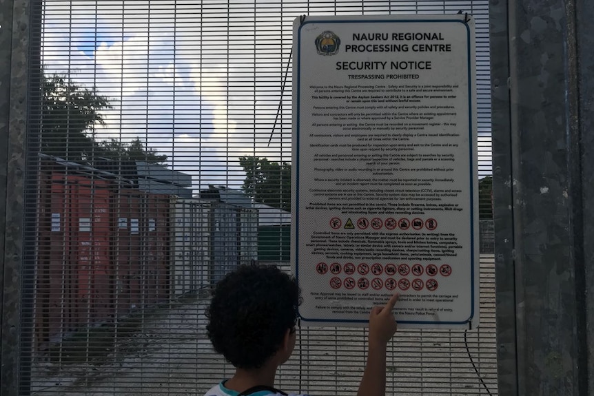 A child points to a security notice sign for the Nauru Regional Processing Centre