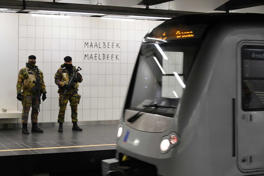 Soldiers stands guard as a train arrives at Maalbeek metro station.