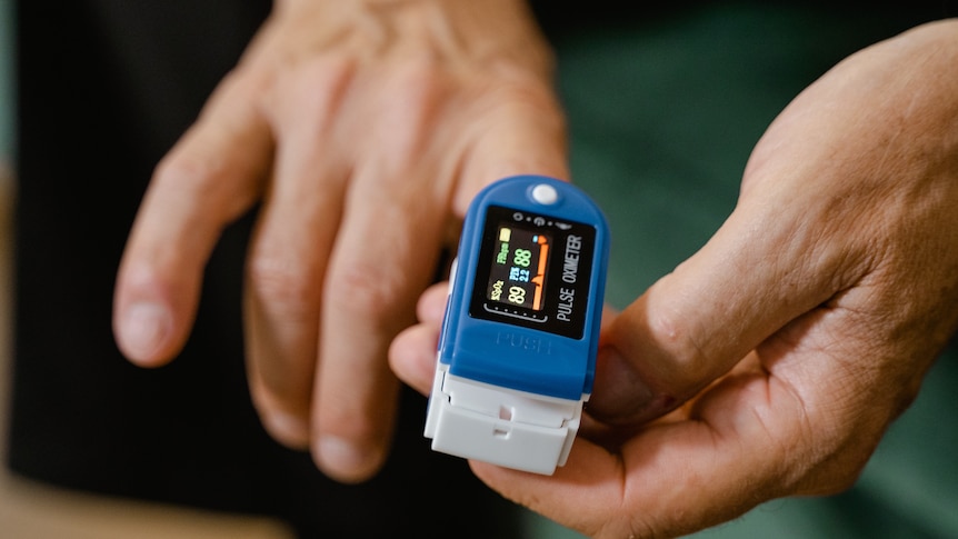 A person attaches a small plastic device to their index finger